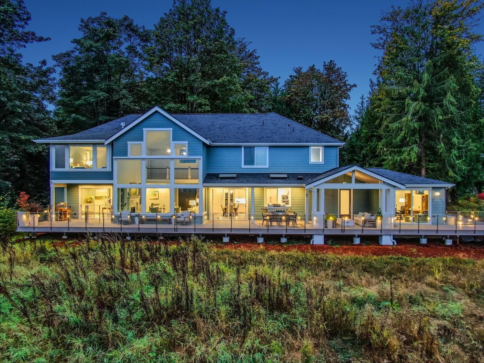 Modern home featuring beautiful exterior lighting, deck lighting, and automated shades designed with smart home technology by Alpha Concepts